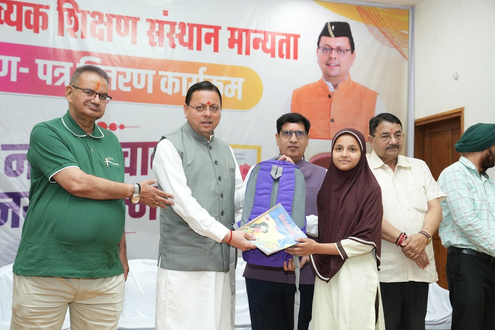 An AIA student in a maroon hijab receiving a backpack and books on stage at a school programme, alongside school and community representatives.